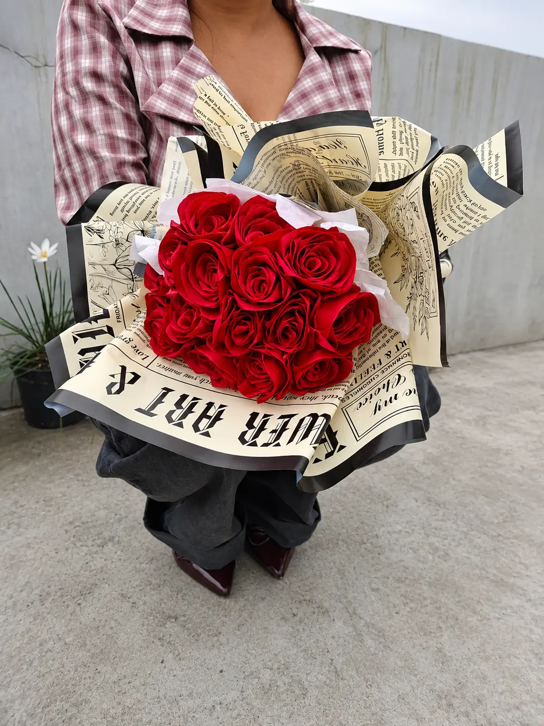 Customer holding a handmade bouquet of red roses in newspaper wrapping